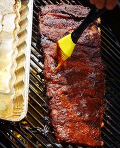 the ribs are being grilled on the grill with a spatula and tongs