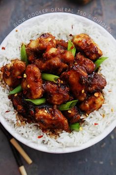 a white bowl filled with rice and chicken on top of a wooden cutting board next to chopsticks