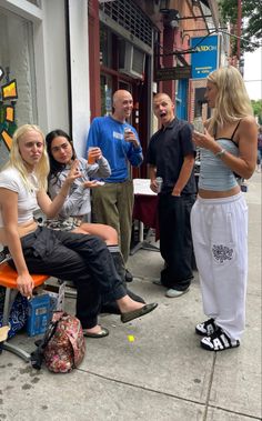 a group of people standing and sitting on the sidewalk