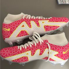 a pair of pink and yellow nike soccer cleats with white laces on them