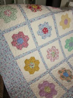 a quilted blanket with flowers on it sitting on a chair next to a window