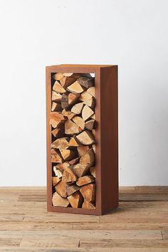 a stack of logs sitting on top of a wooden floor next to a white wall