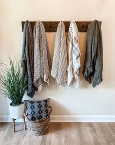 three towels hanging on a coat rack next to a potted plant and a basket