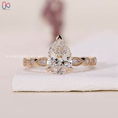 a pear shaped diamond ring on top of a napkin