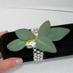 a person is holding onto a black case with a flower on it and pearls around the edge