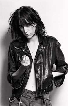 a black and white photo of a young man with long hair wearing a leather jacket