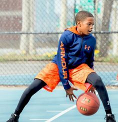 two young boys playing basketball on an outdoor court