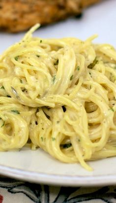 a white plate topped with pasta next to broccoli and other food on a table