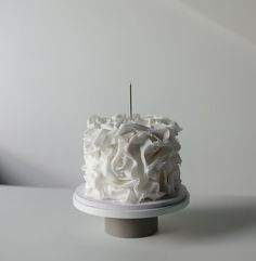 a cake with white frosting and a single candle sticking out of it