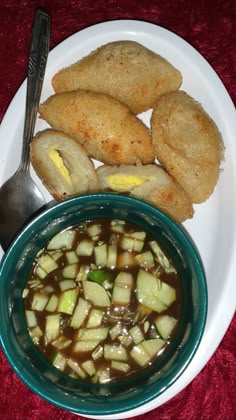 a white plate topped with food next to a bowl of soup