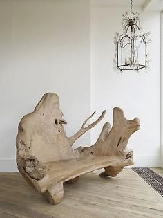 a large piece of driftwood sitting on top of a wooden floor next to a chandelier