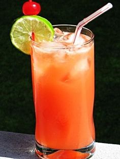 an orange drink with a lime and a cherry on the rim