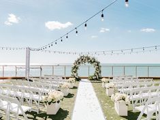 an outdoor ceremony set up with white flowers and greenery on the grass by the ocean