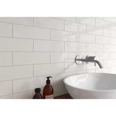 a white bathroom sink sitting under a faucet next to a wall mounted soap dispenser