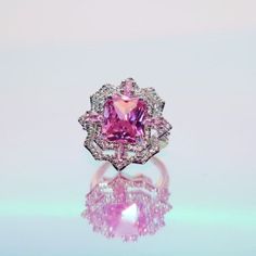 a pink diamond ring sitting on top of a table