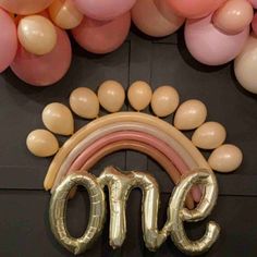 the balloon arch is decorated with gold and pink balloons that spell out'one '