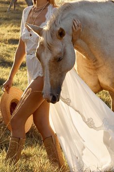 a woman in cowboy boots is petting a horse