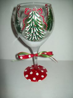 a christmas tree wine glass with polka dots on the bottom and red ribbon around it