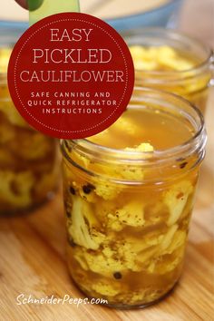 two jars filled with pickled cauliflower sitting on top of a wooden table