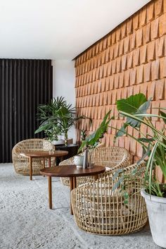 wicker chairs and tables in front of a brick wall with potted plants on it