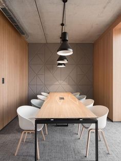 a long table with white chairs and lights hanging from it's ceiling in an office