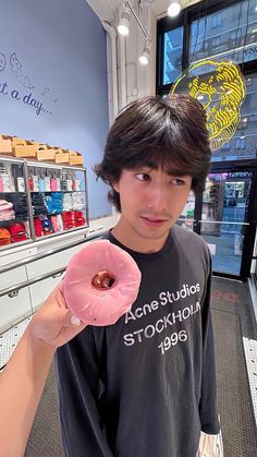 a young man holding a pink donut in his hand