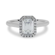 an emerald cut diamond ring with pave set diamonds on the shoulders and sides, in white gold