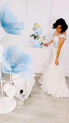 a woman in a white dress standing next to blue flowers