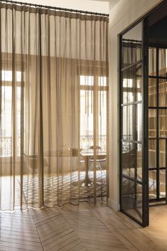 a room with wooden floors and sheer curtains