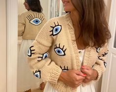 The best-selling Evil Eye Bead Cardigan - a fusion of fashion, tradition, and protection that's guaranteed to turn heads. 🌟 Handcrafted Excellence: Each cardigan is lovingly handcrafted by our skilled artisans, ensuring that you receive a unique piece of artistry with meticulous attention to detail. 👁️ The Turkish Evil Eye: Embrace the ancient protective symbol of the Turkish Evil Eye, believed to ward off negative energy and bring good fortune. It's not just a fashion statement; it's a talism Evil Eye Crochet Sweater, Evil Eye Sweater, Evil Eye Fashion, Eye Sweater, Pretty Sweaters, Cardigan Knitted, Turkish Evil Eye, Beaded Cardigan, Beaded Jacket