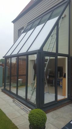 a house with an open roof and glass walls on the outside, next to a small potted plant