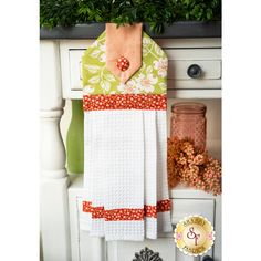 a kitchen towel hanging on the side of a white cabinet next to a potted plant