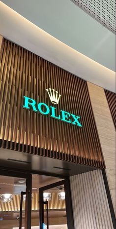 the entrance to rolex is lit up with green letters and crown on it's side