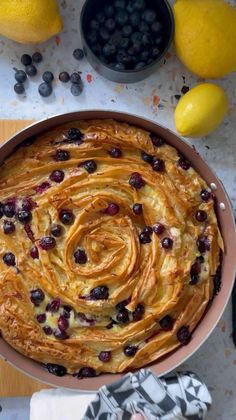 a pan filled with food next to lemons and blueberries