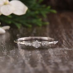 a diamond ring sitting on top of a wooden table next to flowers and greenery