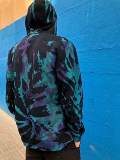 a person wearing a black and blue hoodie standing in front of a blue wall