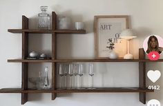 a shelf with wine glasses, candles and pictures on it