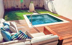 a couch sitting next to a swimming pool on top of a wooden deck