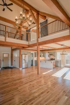 an empty living room with wood floors and chandelier hanging from the rafters