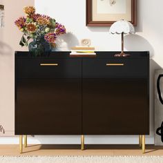 a black and gold sideboard with flowers on top next to a chair in a room