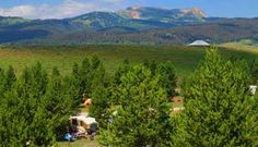 people are camping in the mountains near some trees