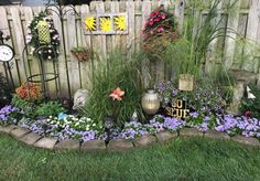 a garden filled with lots of different types of flowers and plants next to a fence