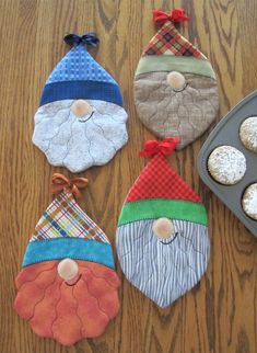 four oven mitts decorated to look like santa claus and other christmas decorations on a table