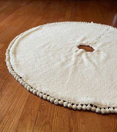 a white round rug with pom poms on the floor