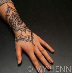 a woman's hand with a henna tattoo on her left arm and wrist