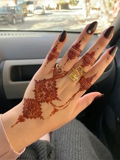 a woman's hand with henna on it in the back seat of a car