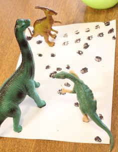 two toy dinosaurs on top of a piece of paper