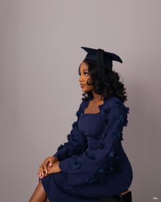 a woman in a graduation gown sitting on a stool