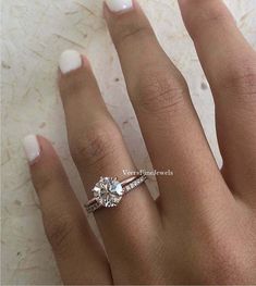 a woman's hand with a diamond ring on top of her finger and white nail polish