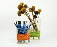 two vases filled with different types of pens and pencils next to each other